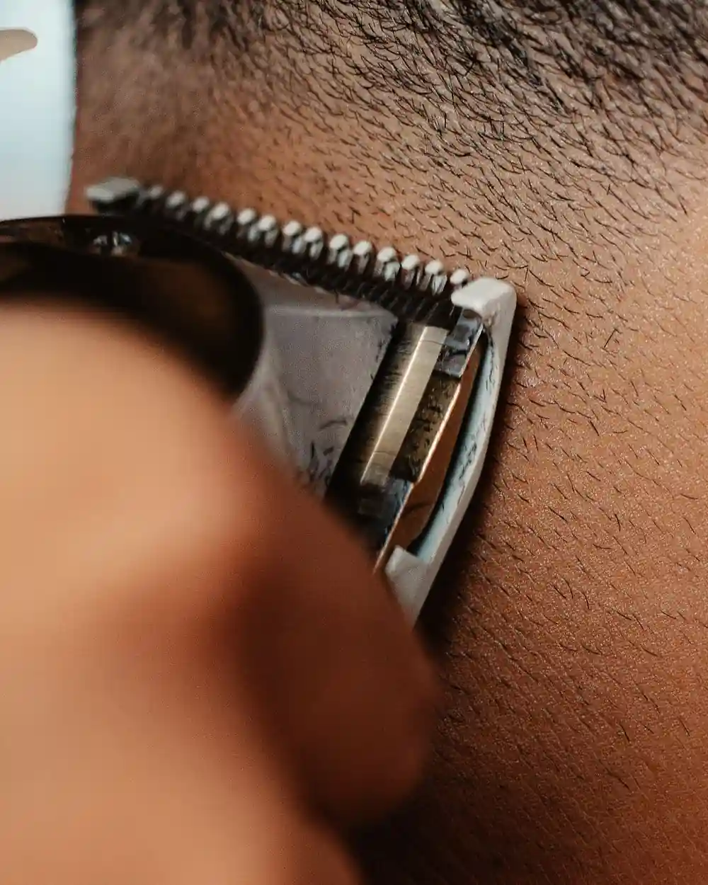 Close-up of a trimmer blade tidying a client's hairline